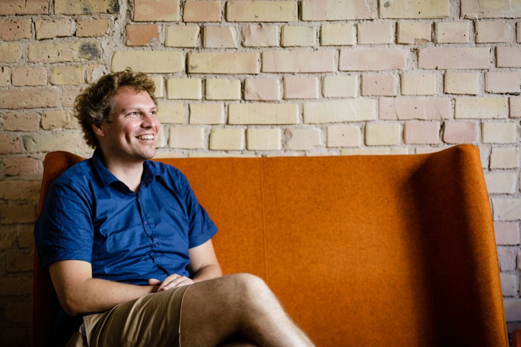 Prof. Dr. Felix Creutzig sitzt auf einem orangen Sofa und lächelt