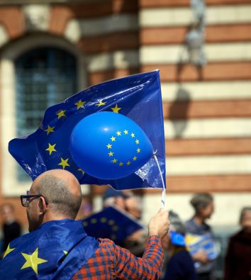 Mann mit zwei EU-Flaggen und einem EU-Ballon