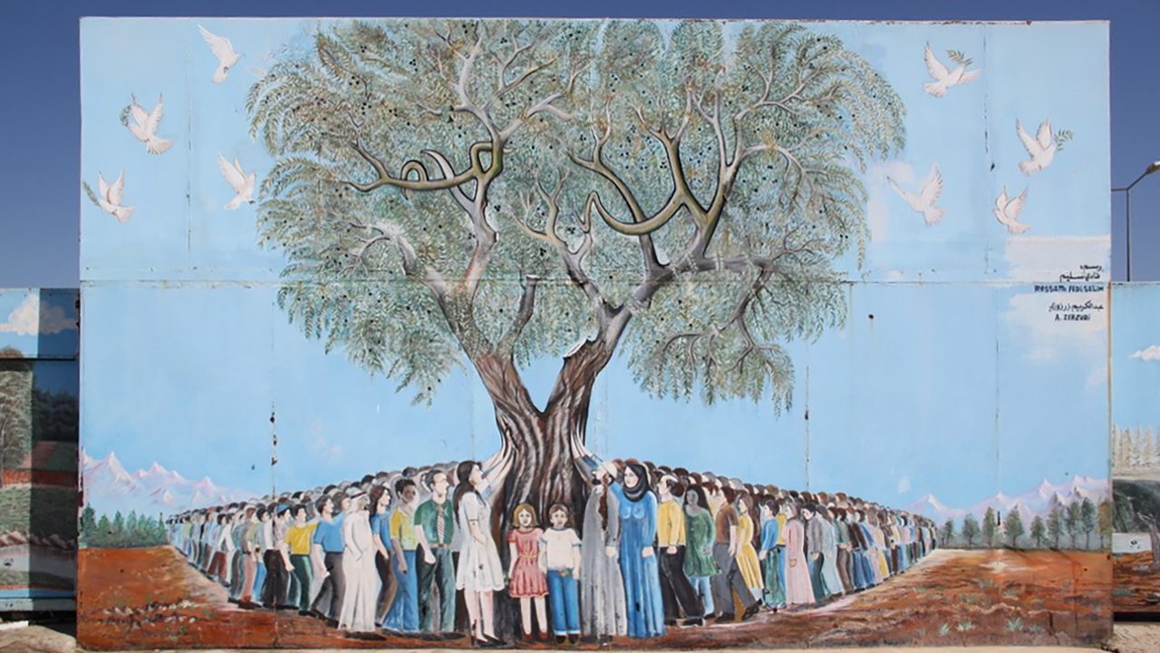 Eine Wandmalerei: Menschen versammeln sich um einen Baum.