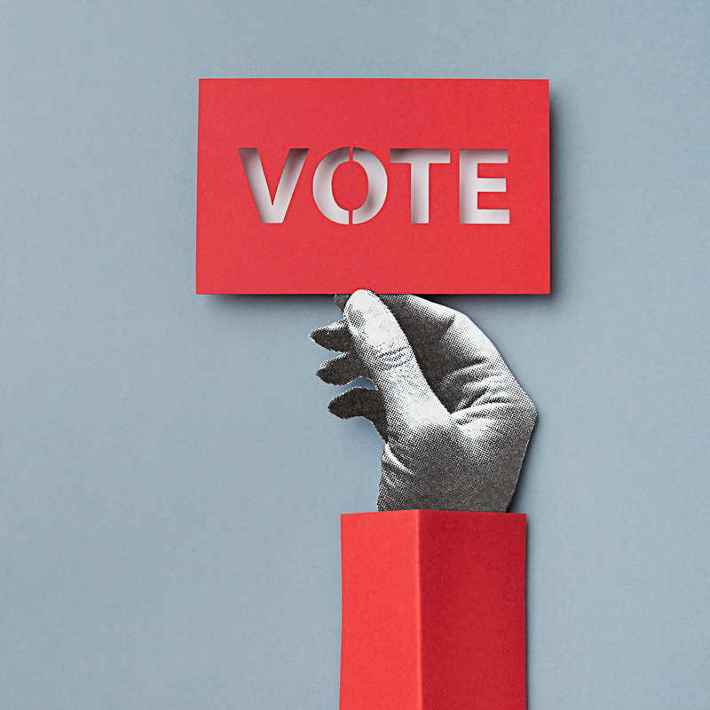 Hand hält Karte mit Aufschrift "VOTE"