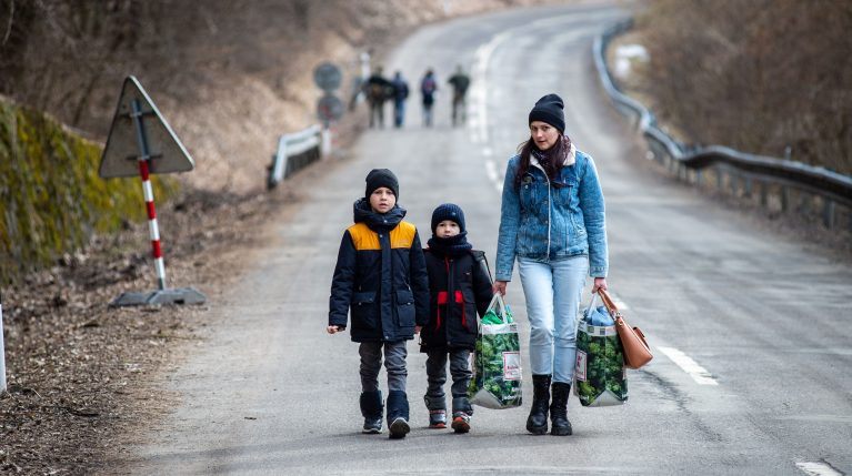Eine Mutter ist mit ihren Kindern zu Fuß unterwegs auf der Flucht.